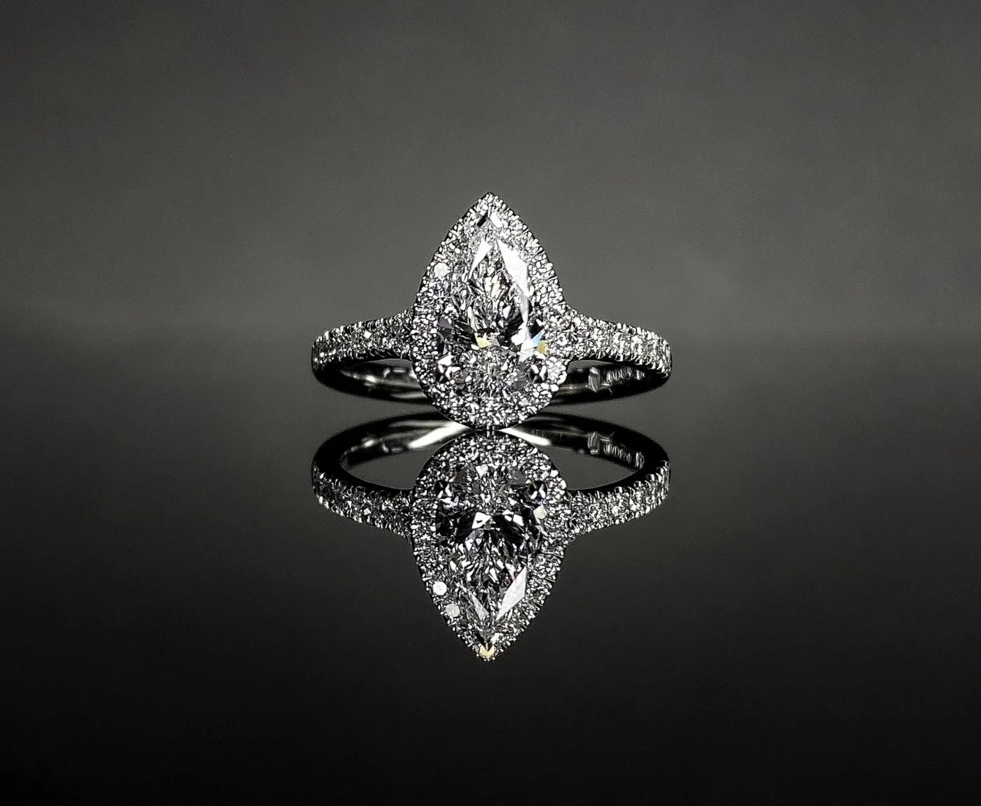 Pear cut engagement ring with halo and side stones in platinum