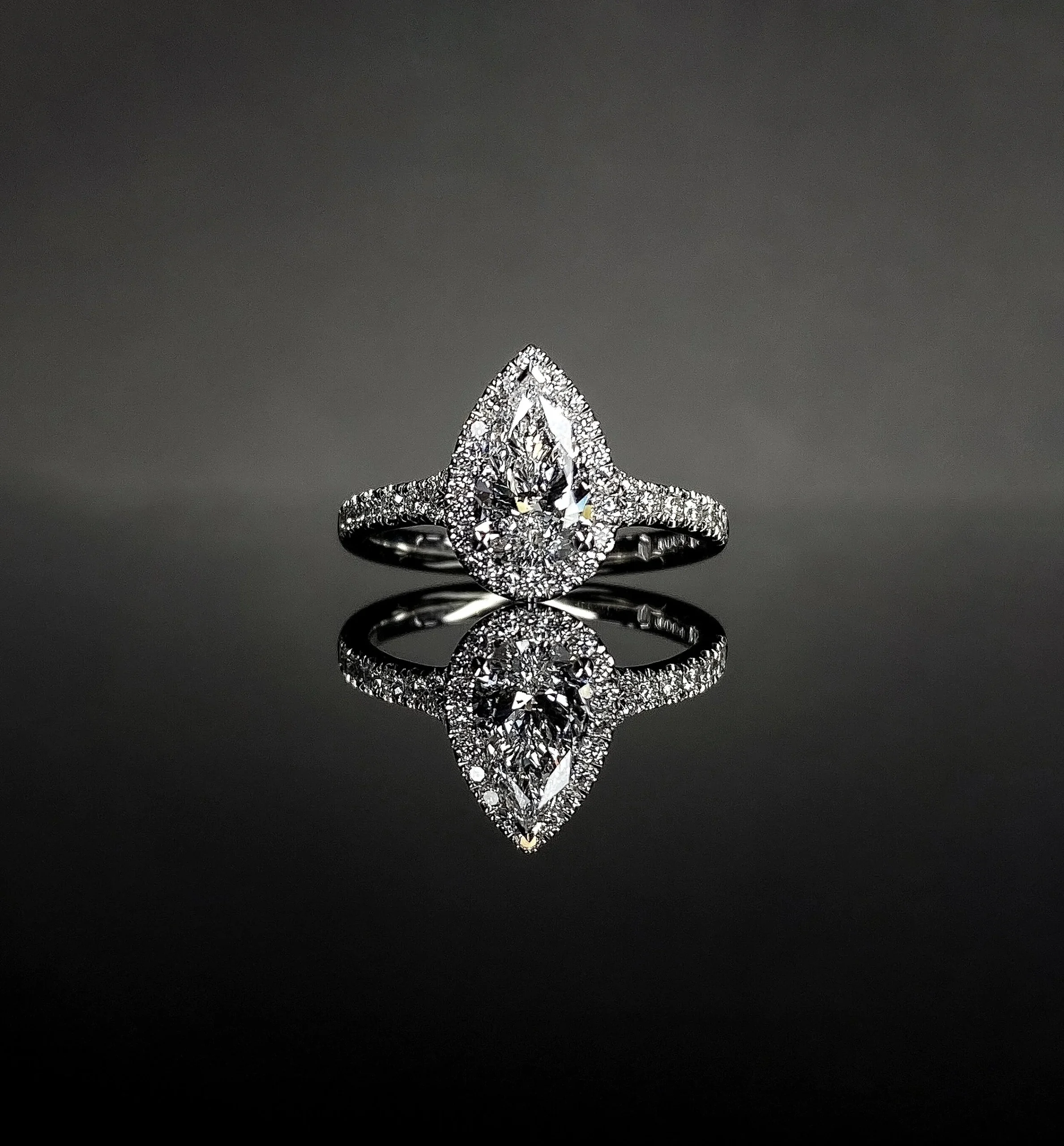 Pear cut engagement ring with halo and side stones in platinum