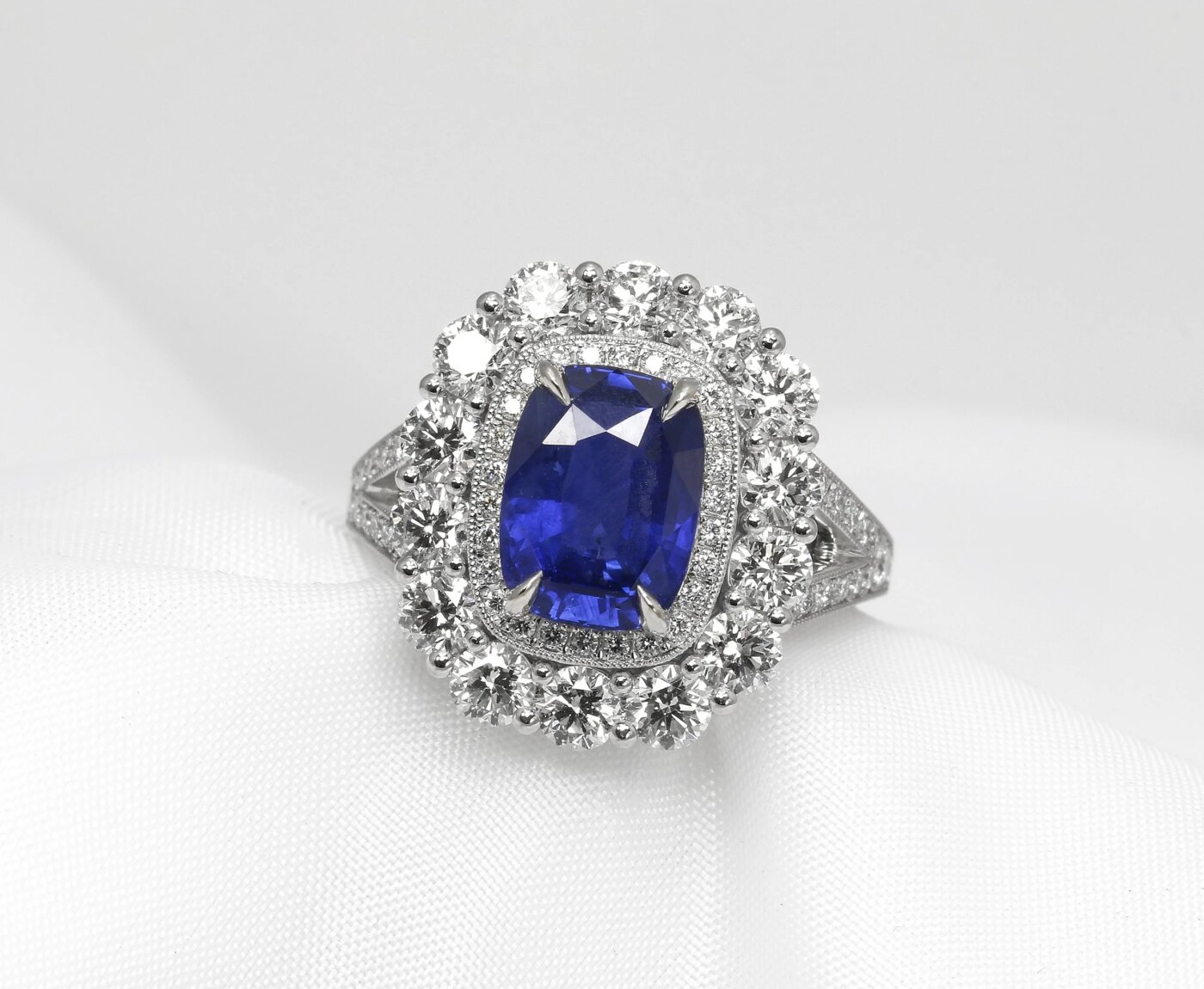 blue sapphire cluster ring, set with a central 3.81ct oblong faceted blue sapphire, surrounded by two halos of diamonds.